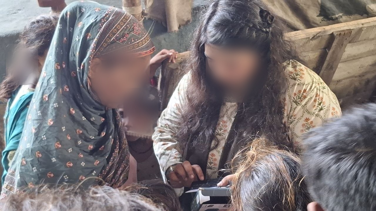 Partager — une femme explique le lecteur à une autre, Pakistan. Visages floutés pour protéger la vie privée.